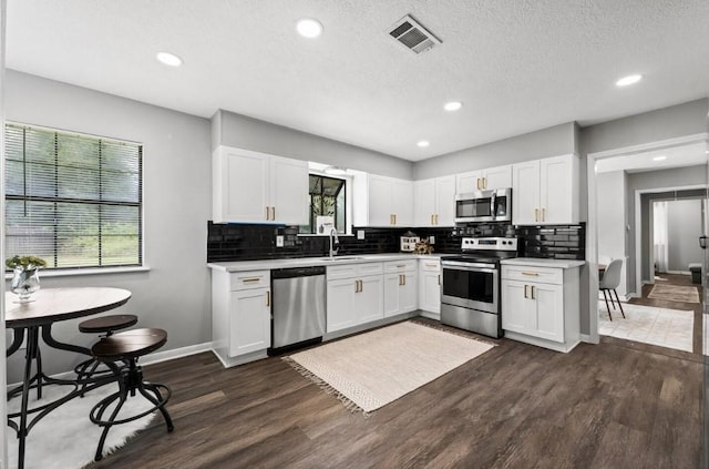 7280 Click Dr, Beaumont, TX 77708 - kitchen with appliances with stainless steel finishes, healthy amount of natural light, dark wood-type flooring, white cabinets, and recessed lighting