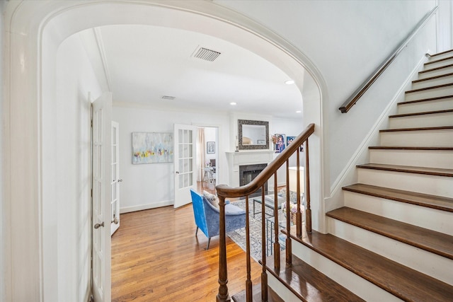 2256 Dryden Rd, Houston, TX 77030 - stairs featuring arched walkways, wood finished floors, a fireplace, recessed lighting, and french doors