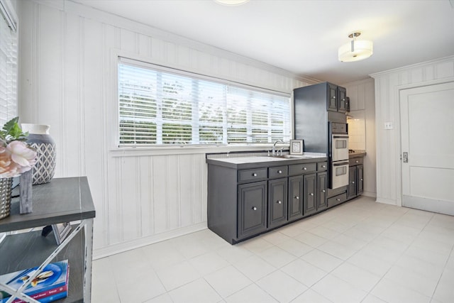 2256 Dryden Rd, Houston, TX 77030 - kitchen with baseboards, a sink, stainless steel double oven, ornamental molding, and light tile patterned floors
