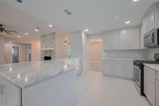 8314 Burning Hills Dr, Houston, TX 77071 - kitchen featuring stainless steel appliances, a ceiling fan, open floor plan, light stone countertops, and recessed lighting