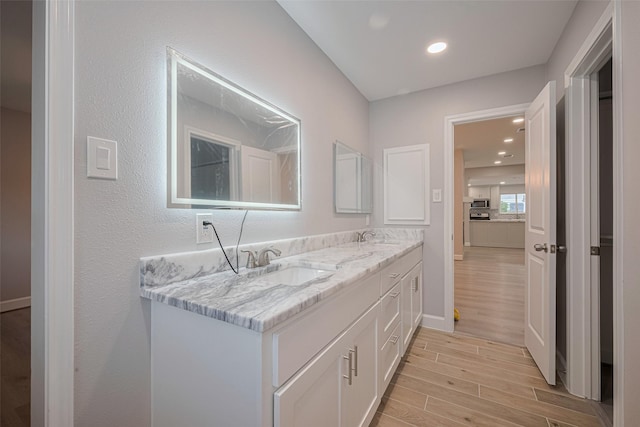 8314 Burning Hills Dr, Houston, TX 77071 - bathroom with wood finished floors, double vanity, baseboards, recessed lighting, and a textured wall
