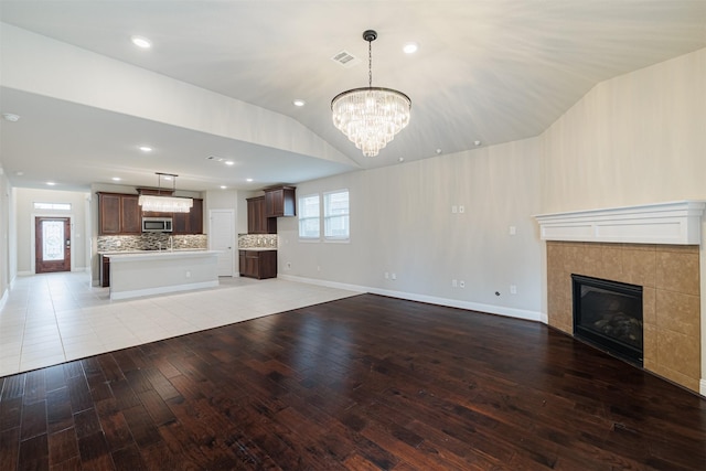 16719 Highland Country Dr, Cypress, TX 77433 - unfurnished living room featuring light wood-style floors, a chandelier, a tile fireplace, lofted ceiling, and baseboards