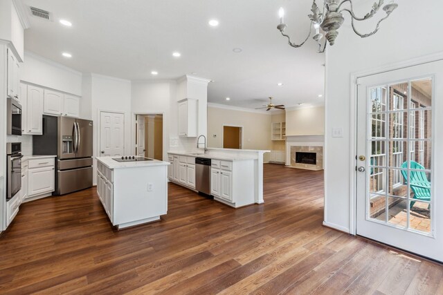 1327 Mission Chase Dr, Houston, TX 77077 - kitchen with stainless steel appliances, ornamental molding, a peninsula, white cabinetry, and dark wood-style floors