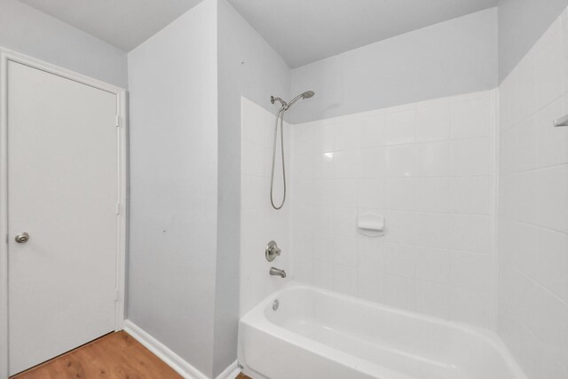 12047 Madison Oak St, Houston, TX 77038 - bathroom with washtub / shower combination, wood finished floors, and baseboards