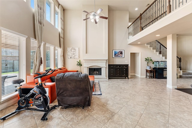 10827 Naburn Gate, Richmond, TX 77407 - living area featuring a high ceiling, a ceiling fan, stairway, baseboards, and a fireplace with raised hearth
