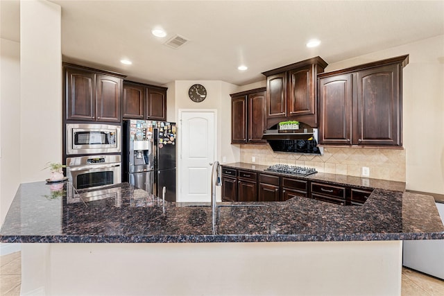 10827 Naburn Gate, Richmond, TX 77407 - kitchen with appliances with stainless steel finishes, dark brown cabinets, backsplash, dark stone countertops, and recessed lighting