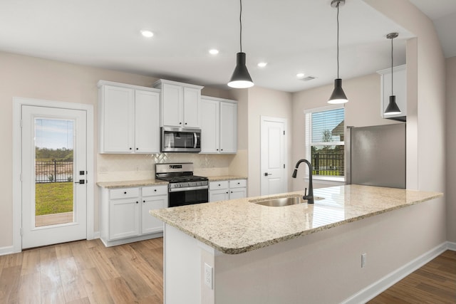 3029 Sorrento Hill Dr, Katy, TX 77493 - kitchen featuring appliances with stainless steel finishes, a peninsula, light wood-style floors, white cabinets, and tasteful backsplash