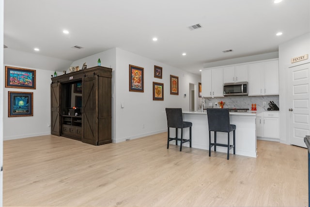 30114 Ousel Falls Ln, Fulshear, TX 77494 - kitchen featuring stainless steel microwave, decorative backsplash, white cabinets, recessed lighting, and light wood-style floors