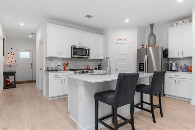 30114 Ousel Falls Ln, Fulshear, TX 77494 - kitchen featuring stainless steel appliances, light wood-style flooring, backsplash, a breakfast bar, and recessed lighting