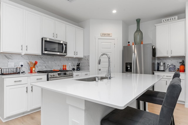 30114 Ousel Falls Ln, Fulshear, TX 77494 - kitchen with stainless steel appliances, a sink, light wood-style floors, decorative backsplash, and recessed lighting