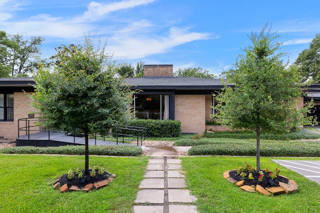 1403 N Thompson St, Conroe, TX 77301 - view of front of house with brick siding, a front lawn, and a chimney