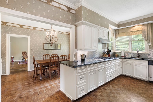 1403 N Thompson St, Conroe, TX 77301 - kitchen featuring a chandelier, wallpapered walls, appliances with stainless steel finishes, white cabinets, and a sink