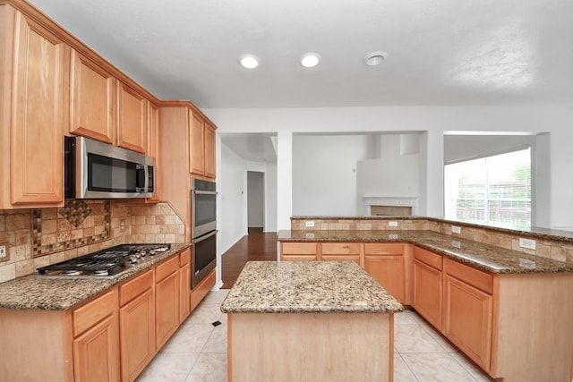 1605 Spring Glen Ln, Pearland, TX 77581 - kitchen with stainless steel appliances, a kitchen island, decorative backsplash, light stone countertops, and light tile patterned floors