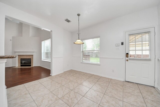 1605 Spring Glen Ln, Pearland, TX 77581 - unfurnished dining area with a tiled fireplace, light tile patterned floors, and baseboards