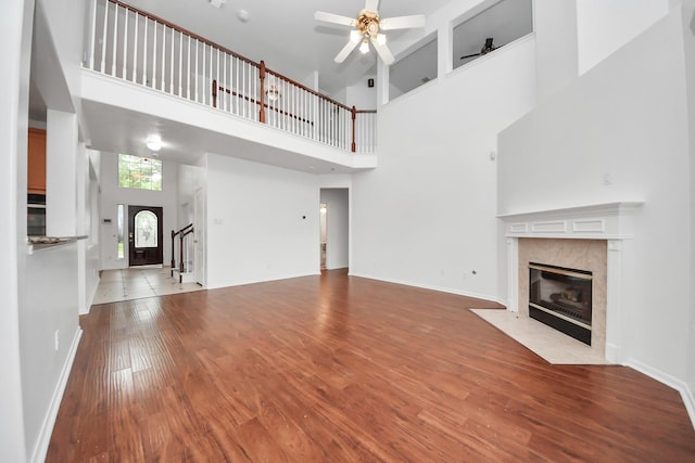 1605 Spring Glen Ln, Pearland, TX 77581 - unfurnished living room with a fireplace, ceiling fan, a towering ceiling, wood finished floors, and stairway