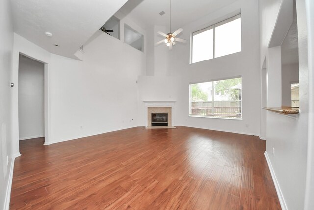 1605 Spring Glen Ln, Pearland, TX 77581 - unfurnished living room with ceiling fan, wood finished floors, a fireplace, a high ceiling, and baseboards
