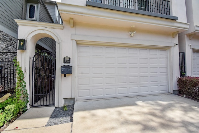 4220 Law St, Houston, TX 77005 - view of exterior entry with a balcony, a garage, stucco siding, a gate, and driveway