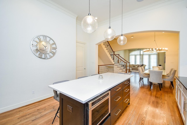 4220 Law St, Houston, TX 77005 - kitchen featuring crown molding, arched walkways, a breakfast bar area, a center island, and light wood-type flooring