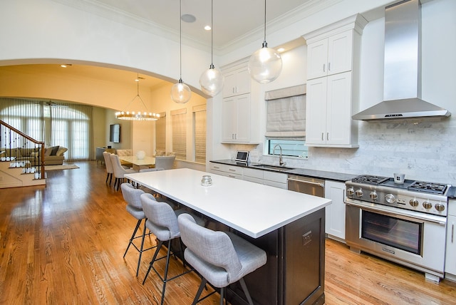 4220 Law St, Houston, TX 77005 - kitchen with stainless steel appliances, wall chimney range hood, a sink, ornamental molding, and arched walkways