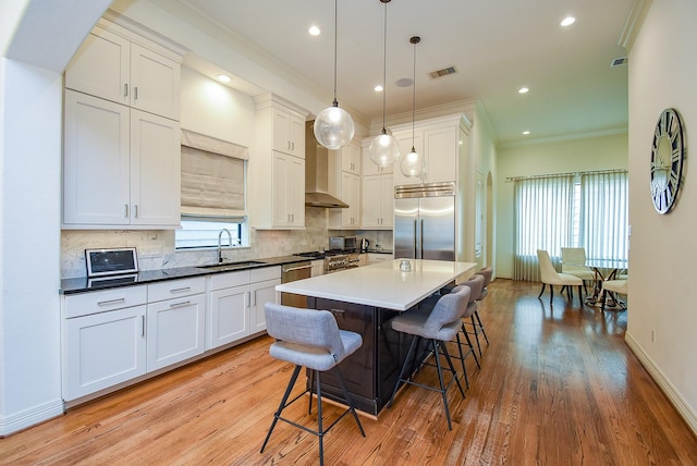 4220 Law St, Houston, TX 77005 - kitchen with built in fridge, a sink, a breakfast bar, light wood-style floors, and crown molding