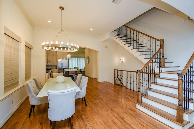 4220 Law St, Houston, TX 77005 - dining space with arched walkways, a chandelier, light wood-style floors, ornamental molding, and stairs