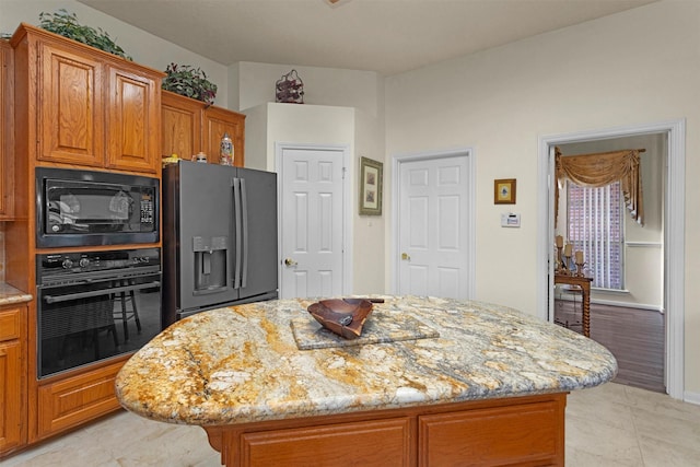 529 Stephen F Austin Dr, Conroe, TX 77302 - kitchen featuring black appliances, light stone countertops, brown cabinets, and a center island