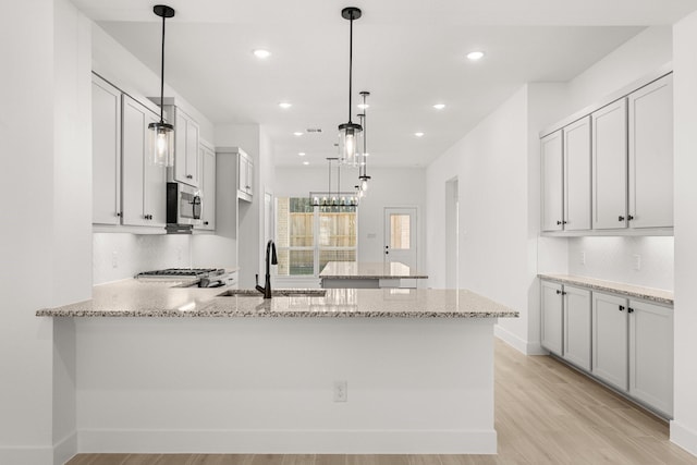 17051 Lilac Paxton Ln, Hockley, TX 77447 - kitchen with a peninsula, stainless steel microwave, a sink, backsplash, and recessed lighting