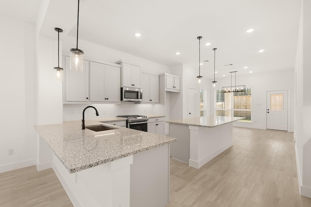 17051 Lilac Paxton Ln, Hockley, TX 77447 - kitchen with appliances with stainless steel finishes, a sink, light wood-style flooring, light stone countertops, and baseboards