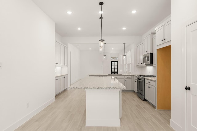 17051 Lilac Paxton Ln, Hockley, TX 77447 - kitchen with appliances with stainless steel finishes, a peninsula, recessed lighting, light stone counters, and pendant lighting