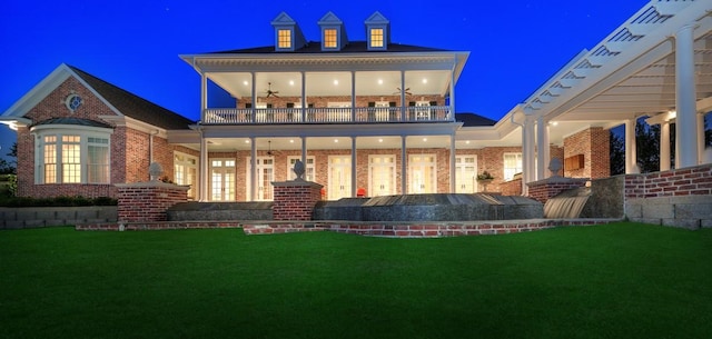 31 Southern Crescent Ct, The Woodlands, TX 77380 - back of house at twilight featuring a balcony, a lawn, and brick siding