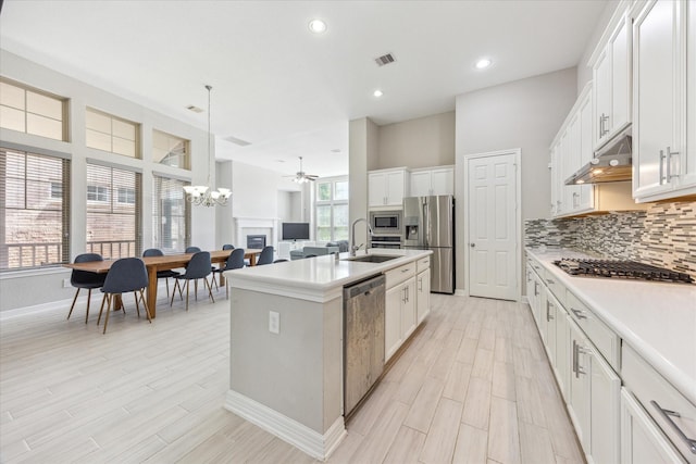9650 Caddo Ridge Ln, Cypress, TX 77433 - kitchen featuring appliances with stainless steel finishes, under cabinet range hood, a sink, a chandelier, and a center island with sink