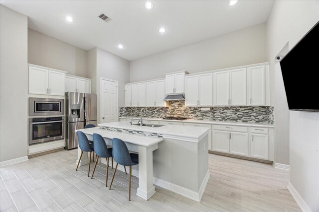 9650 Caddo Ridge Ln, Cypress, TX 77433 - kitchen featuring stainless steel appliances, a sink, under cabinet range hood, tasteful backsplash, and light countertops