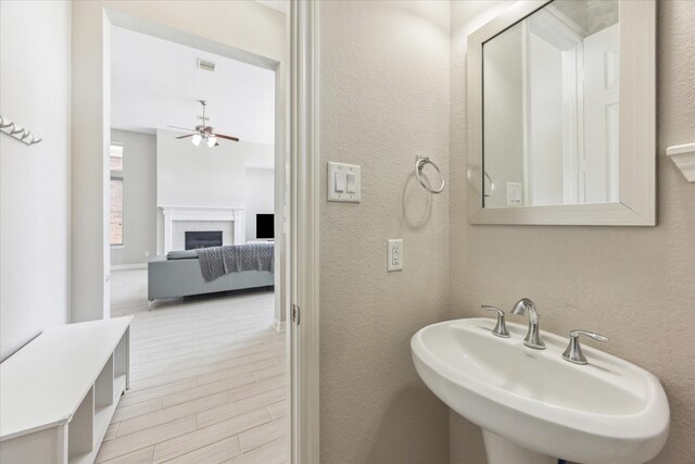 9650 Caddo Ridge Ln, Cypress, TX 77433 - bathroom featuring ceiling fan, a sink, wood finished floors, a textured wall, and a fireplace
