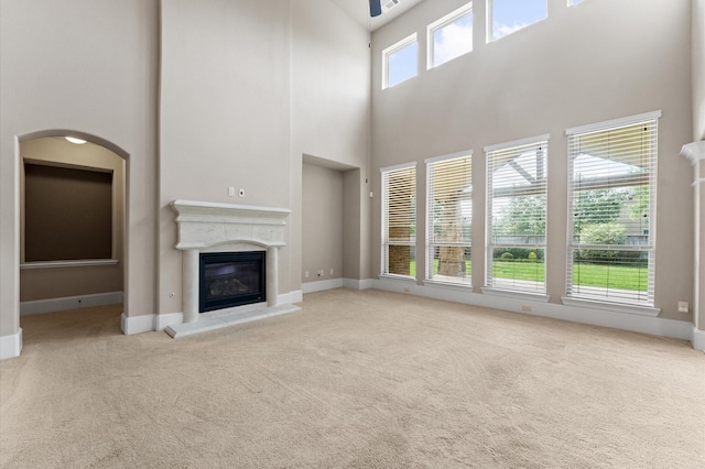 10115 Cypress Path, Missouri City, TX 77459 - unfurnished living room with carpet flooring, a towering ceiling, a glass covered fireplace, and baseboards