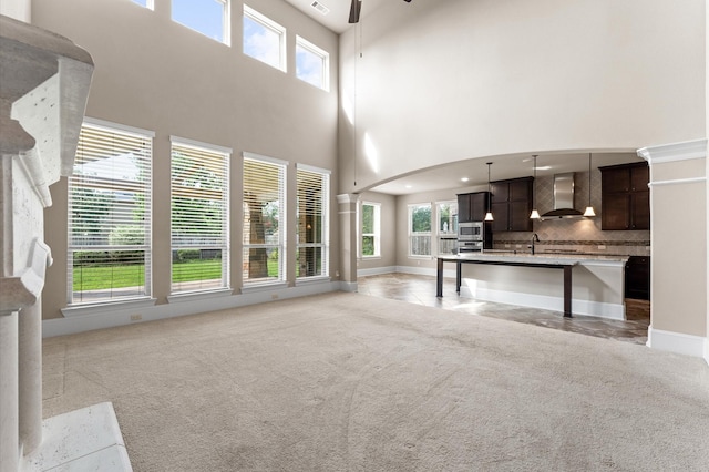 10115 Cypress Path, Missouri City, TX 77459 - unfurnished living room with a ceiling fan, a towering ceiling, plenty of natural light, light colored carpet, and a sink