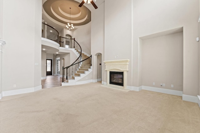 10115 Cypress Path, Missouri City, TX 77459 - unfurnished living room featuring carpet, a ceiling fan, a towering ceiling, a glass covered fireplace, and baseboards