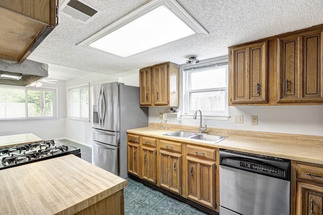 3826 Brier Gardens Dr, Houston, TX 77082 - kitchen featuring a sink, stainless steel appliances, brown cabinetry, and a textured ceiling
