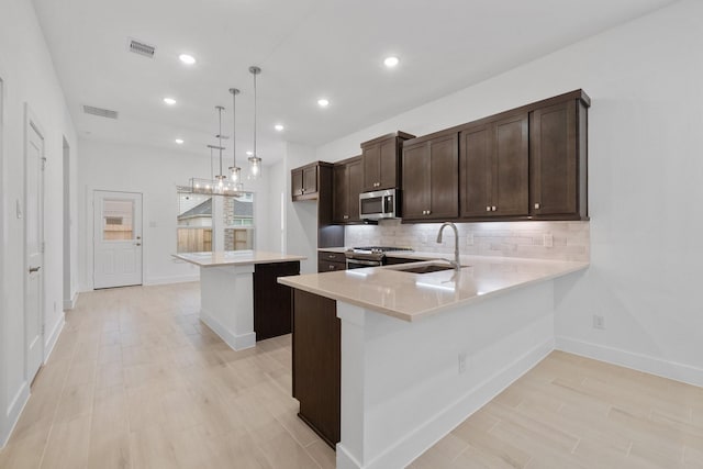 17055 Lilac Paxton Ln, Hockley, TX 77447 - kitchen with appliances with stainless steel finishes, a sink, light countertops, dark brown cabinets, and backsplash