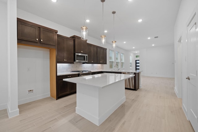 17055 Lilac Paxton Ln, Hockley, TX 77447 - kitchen featuring stainless steel appliances, a sink, a kitchen island, dark brown cabinetry, and light countertops