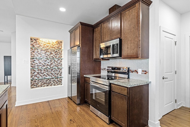 2811 Izamal Ct, Galveston, TX 77554 - kitchen featuring stainless steel appliances, backsplash, light stone counters, light wood-type flooring, and dark brown cabinetry