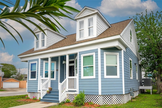 1828 Ursuline St, Galveston, TX 77550 - bungalow featuring central air condition unit, roof with shingles, a detached garage, a front lawn, and an outbuilding