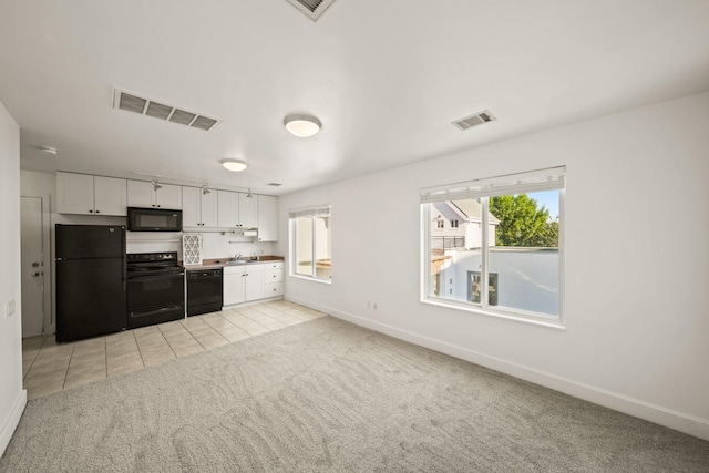 3810 Bellefontaine St, Houston, TX 77025 - kitchen featuring black appliances, light colored carpet, white cabinets, baseboards, and a sink