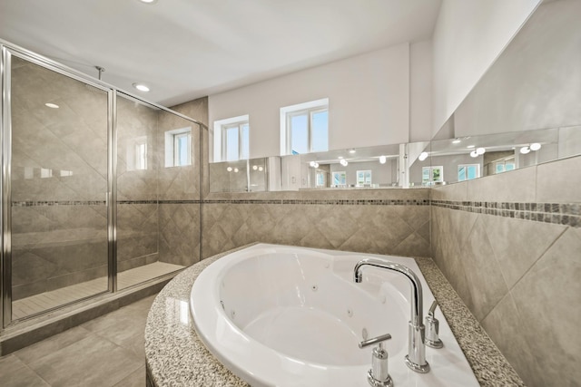 3810 Bellefontaine St, Houston, TX 77025 - bathroom featuring a stall shower, a jetted tub, tile walls, and tile patterned flooring