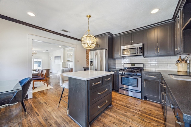 2229 Singleton St, Houston, TX 77008 - kitchen with appliances with stainless steel finishes, ornamental molding, a breakfast bar area, dark wood-type flooring, and decorative backsplash