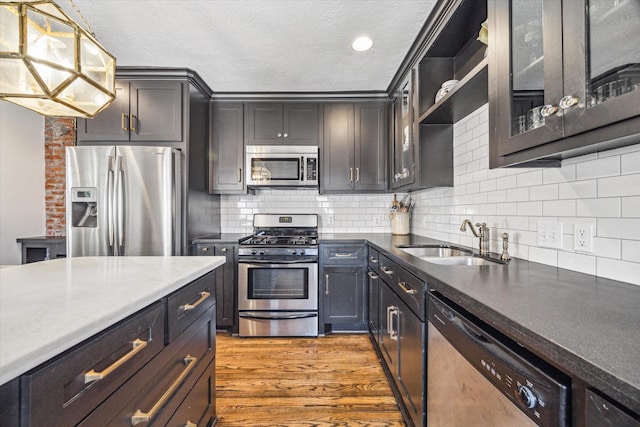 2229 Singleton St, Houston, TX 77008 - kitchen featuring appliances with stainless steel finishes, a sink, dark wood-type flooring, a textured ceiling, and tasteful backsplash