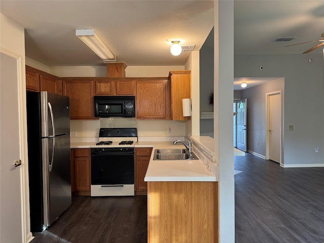 7340 Muffin Dr, Austin, TX 78724 - kitchen featuring freestanding refrigerator, black microwave, gas stove, a sink, and dark wood-style floors