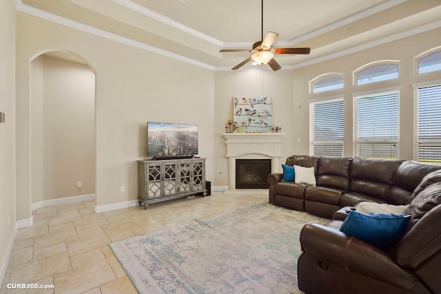 1522 Richland Hollow Ln, Friendswood, TX 77546 - tiled living area with a tray ceiling, a ceiling fan, arched walkways, ornamental molding, and a glass covered fireplace