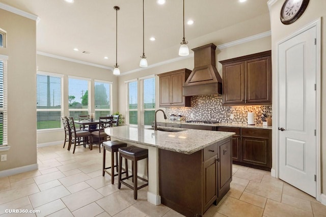 1522 Richland Hollow Ln, Friendswood, TX 77546 - kitchen with a sink, custom range hood, backsplash, baseboards, and an island with sink