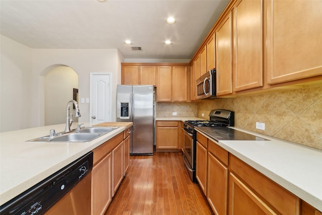 24526 Carlton Springs Ln, Katy, TX 77494 - kitchen with appliances with stainless steel finishes, a sink, arched walkways, wood finished floors, and light countertops