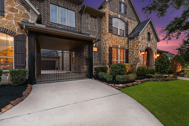 5702 Mustang Ridge Ln, Fulshear, TX 77441 - view of front of house with stone siding, a gate, concrete driveway, and a yard